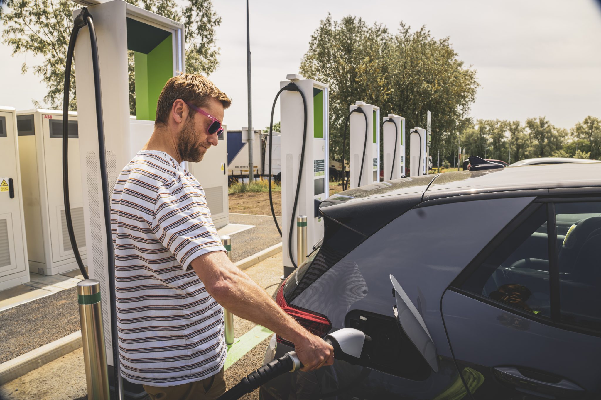 Man holding a GRIDSERVE EV charger by a car